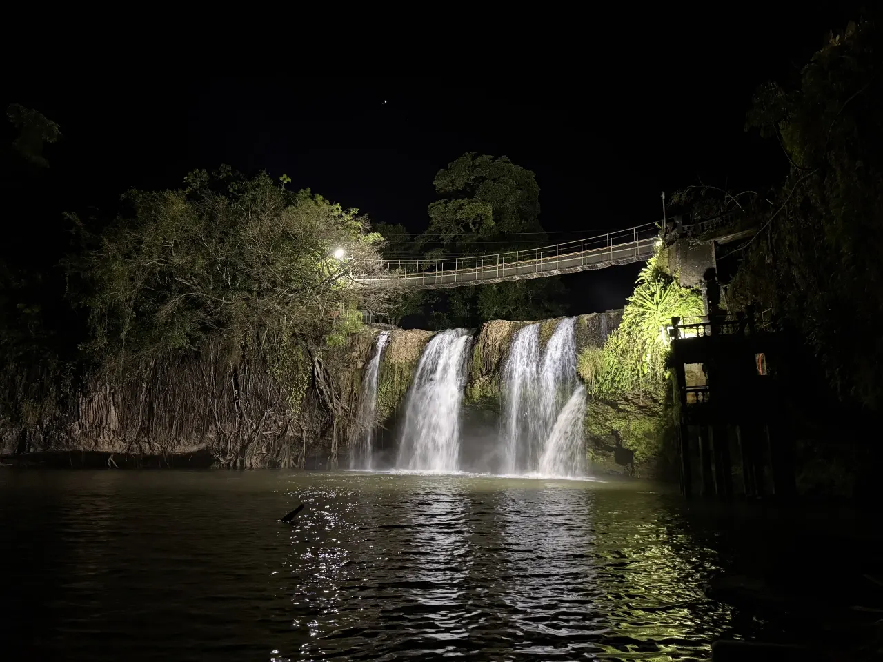 Mena Creek Falls and suspension bridge lit up after dark